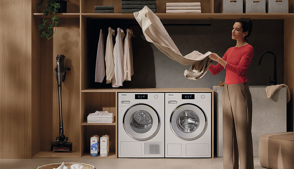Vrouw vouwt wasgoed uit Miele wasdroger met DryCare 40 in moderne wasruimte