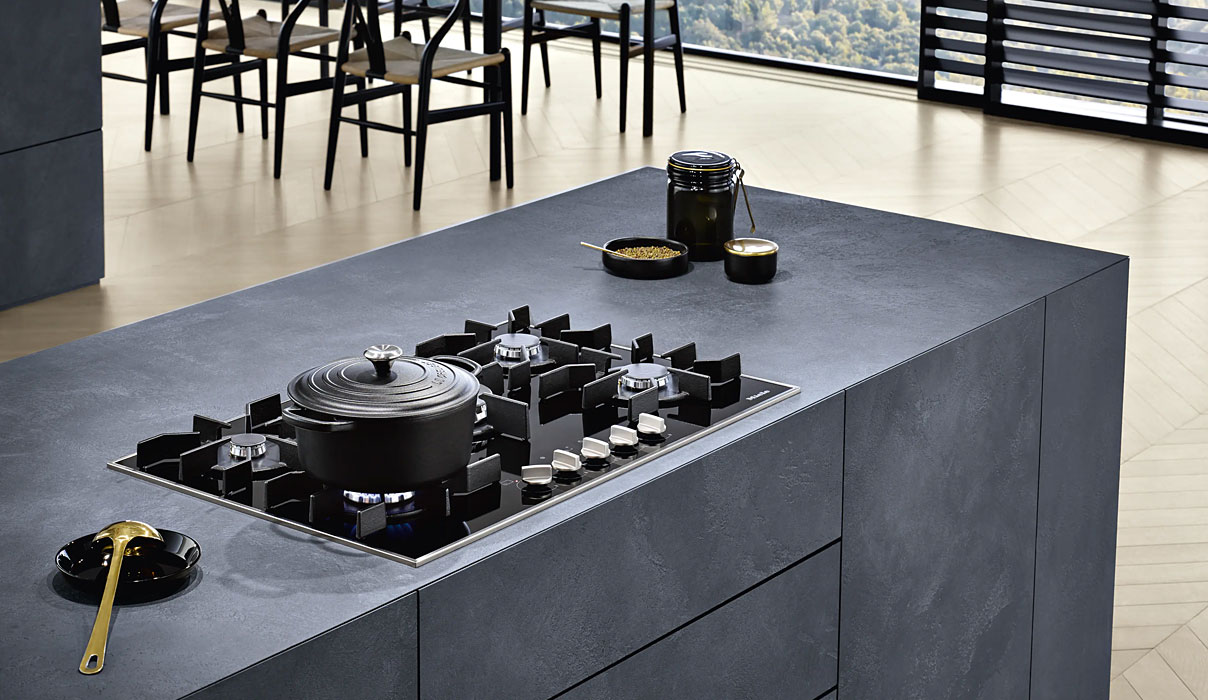 Miele gaskookplaat in moderne keuken met gietijzeren pannendragers en brandende gasvlam