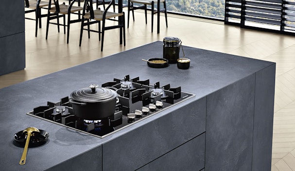 Miele gaskookplaat in moderne keuken met gietijzeren pannendragers en brandende gasvlam