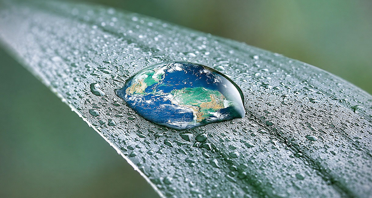 Waterdruppel in de vorm van de aarde op een blad als symbool voor zuinig verbruik