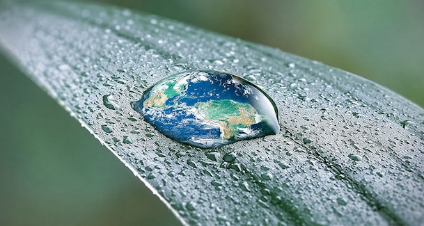 Waterdruppel in de vorm van de aarde op een blad als symbool voor zuinig verbruik