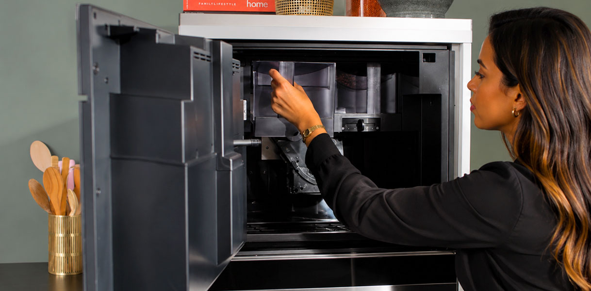 Vrouw neemt het waterreservoir aan de voorkant uit een Miele inbouw koffiemachine