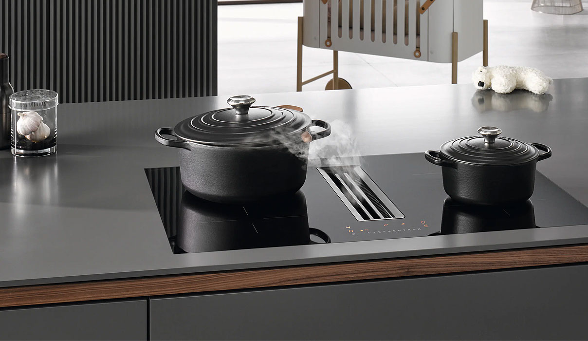 Miele inductiekookplaat met werkbladafzuiging en twee zwarte pannen in moderne keuken