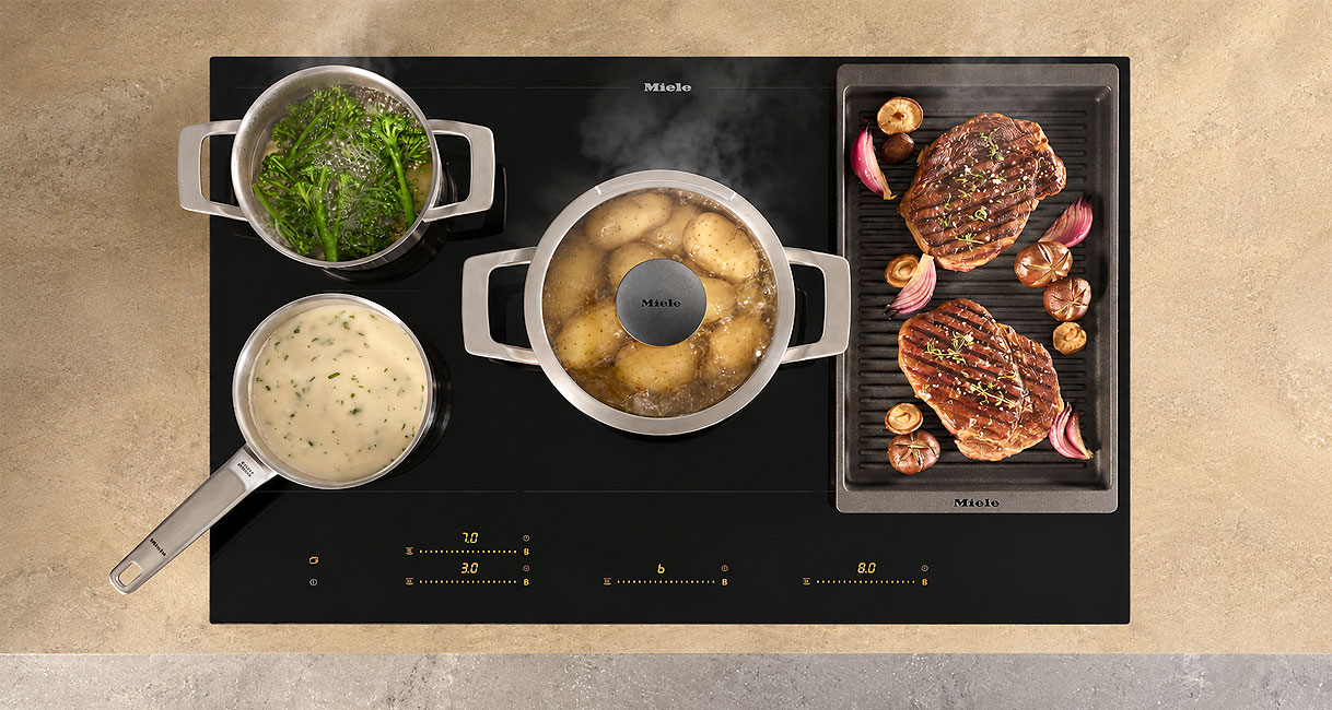 Inductiekookplaat met pannen op zones en grillplaat met steaks op gekoppeld PowerFlex vlak
