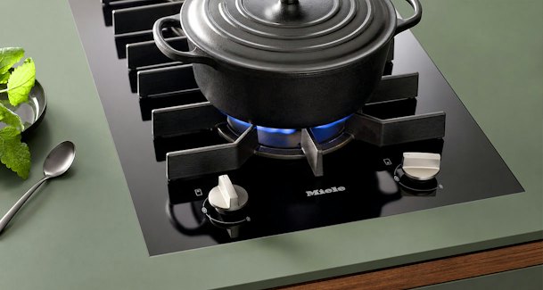 Gaskookplaat met gietijzeren braadpan op brander met zichtbare blauwe vlam