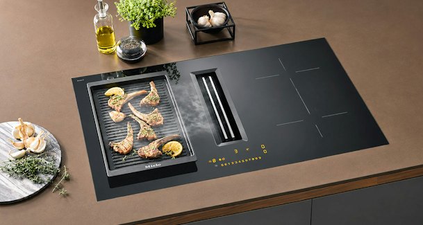 Inductie kookplaat met ingebouwde afzuiging die damp van grillplaat met lamskoteletten afvangt