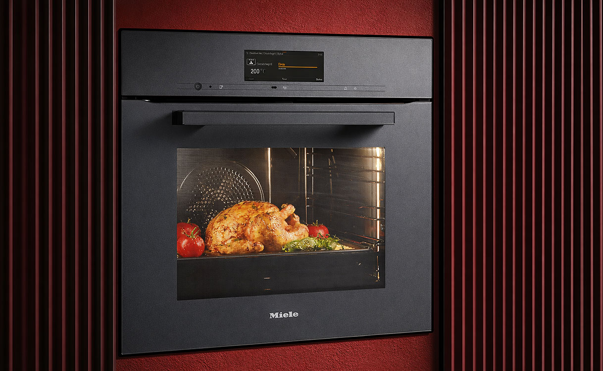 Miele inbouw magnetron met kipgerecht in ovenruimte en warme verlichting in luxe wandopstelling