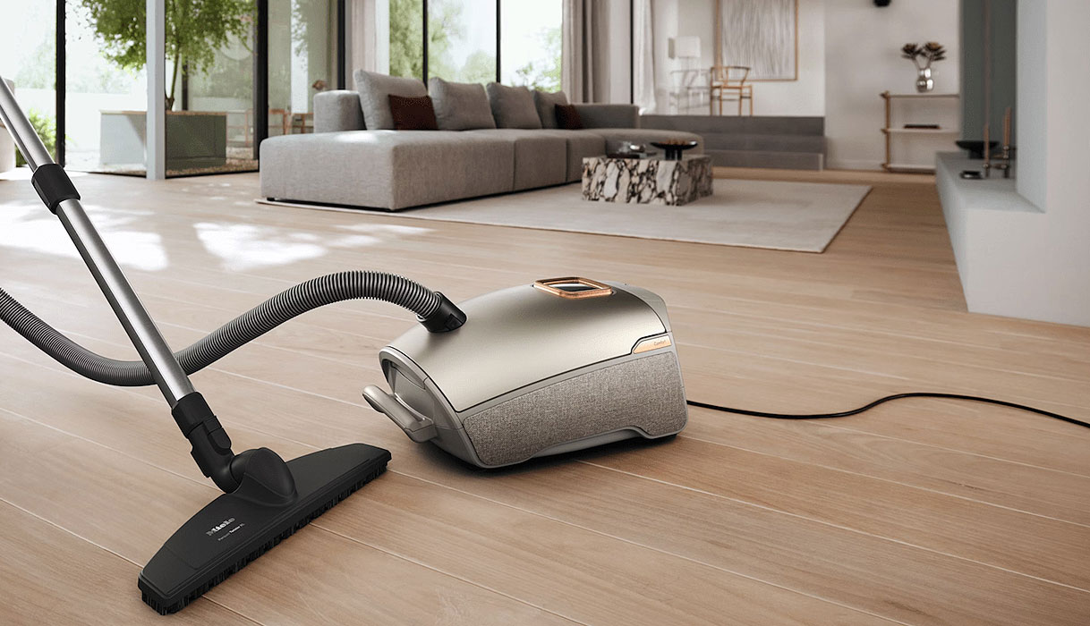 Miele stofzuiger met zak op houten vloer in moderne woonkamer