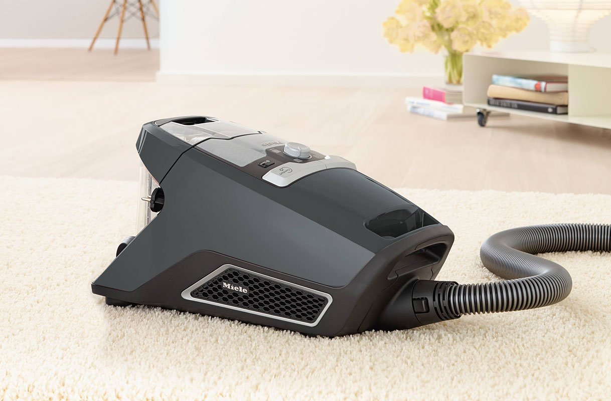 Miele stofzuiger zonder zak met doorzichtige stofcontainer op zacht vloerkleed