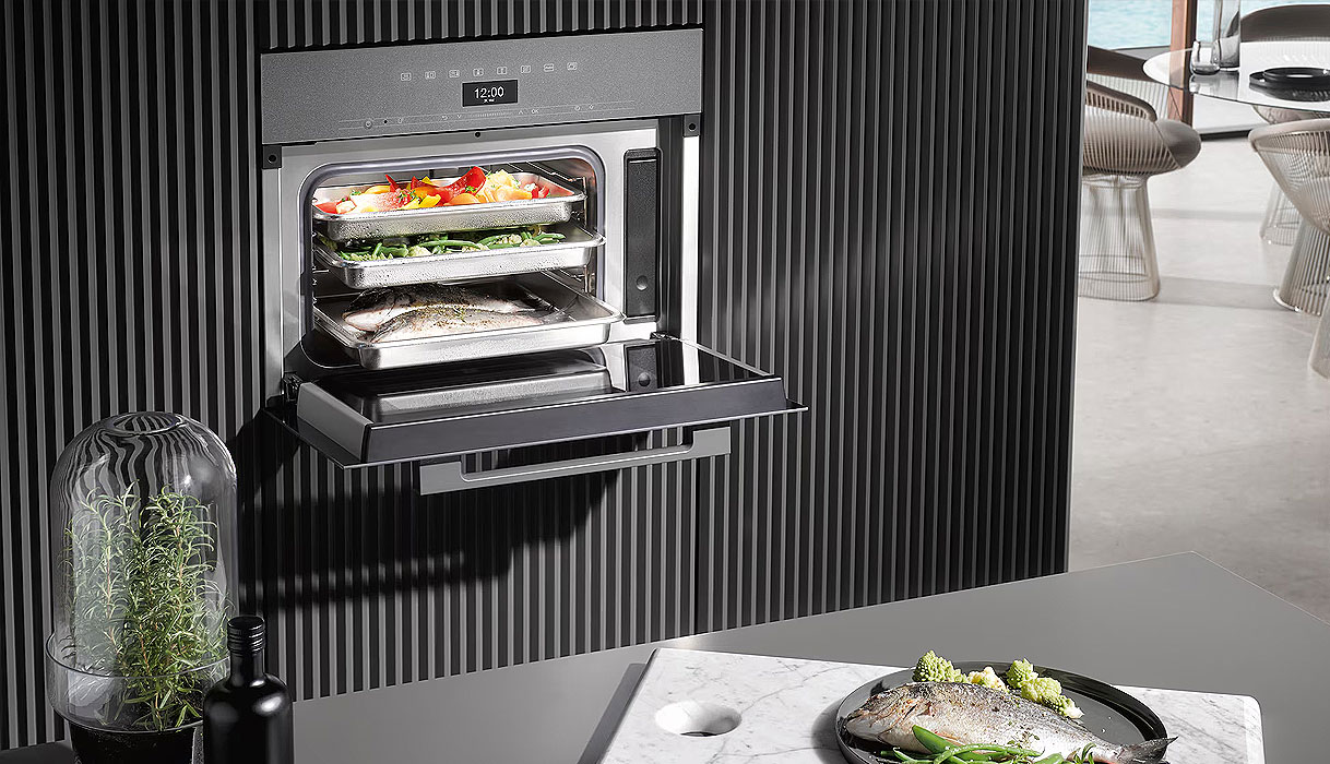 Geopende Miele stoomoven met verse gerechten op meerdere niveaus in een moderne keuken