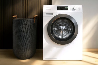 Miele voorlader wasmachine met modern design naast wasmand, duurzaam en flexibel in gebruik