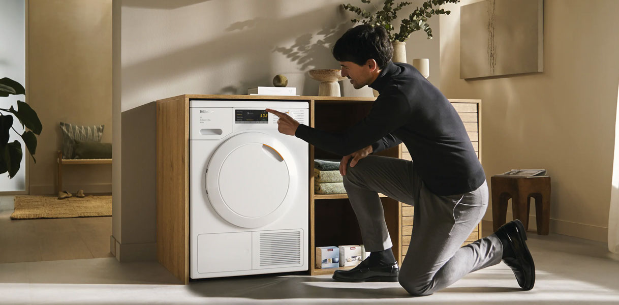 Man laadt was in Miele warmtepompdroger in moderne woonkamer bekend om sterke bouwkwaliteit en lange levensduur