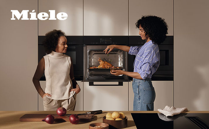 Twee vrouwen bij een Miele inbouwoven met gebraden kip