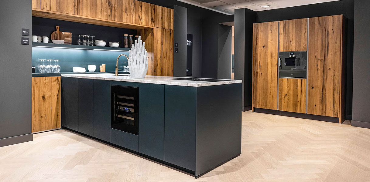Modern schiereiland keuken met greeploze fronten, donker kookeiland en houten kastenwand