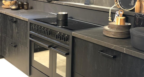 Modern zwart gasfornuis met inductie kookplaat.