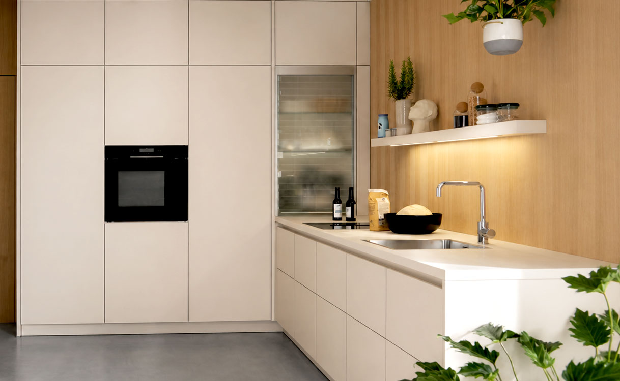 Moderne hoekkeuken met greeploze beige fronten, houten achterwand en wit keramisch werkblad