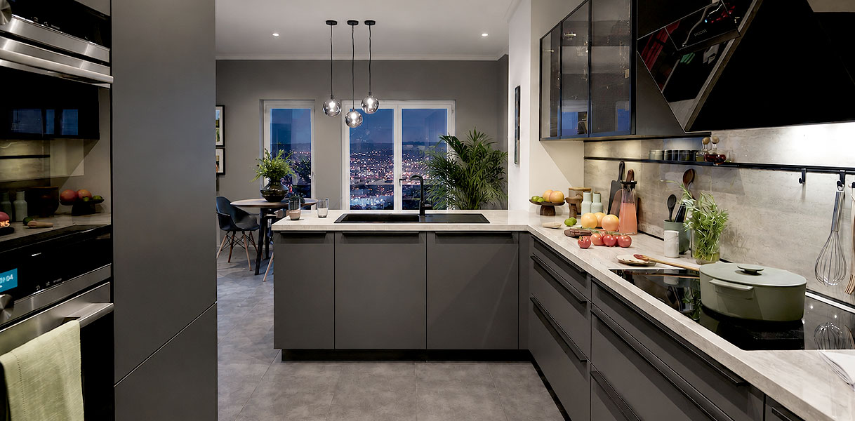 Moderne L-vorm keuken in open woonkeuken met hanglampen en betonlook werkblad