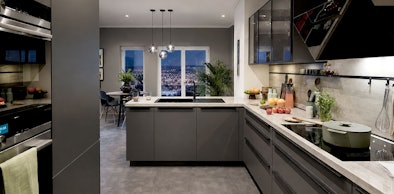 Moderne L-vorm keuken in open woonkeuken met hanglampen en betonlook werkblad