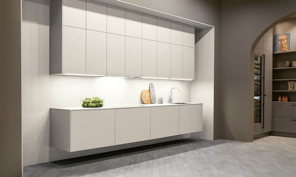 Minimalistische moderne rechte keuken met greeploze matgrijze fronten, zwevende onderkasten en een strak wit werkblad in een rustige designruimte.
