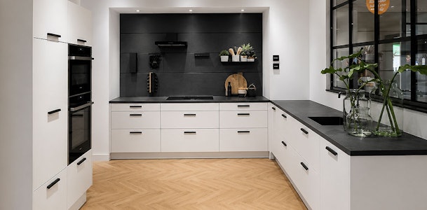 Moderne witte keuken met zwarte grepen, donker werkblad en matzwarte accenten