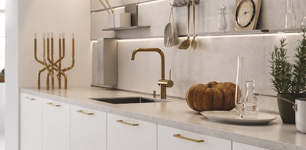Witte keuken met messing grepen, gouden kraan en lichte achterwand