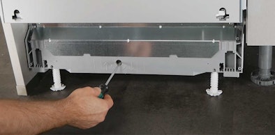 Monteur stelt vaatwasser waterpas af met schroevendraaier aan de voorzijde.