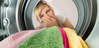 Vrouw knijpt haar neus dicht bij het openen van de wasmachine