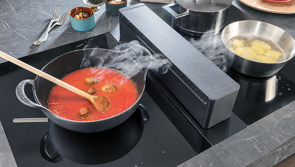 Novy Up uitschuifbare afzuigtoren tussen pan tomatensaus en pan kokende aardappelen
