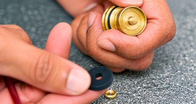 Gedemonteerd binnenwerk van keukenkraan met rubberen ring en sluitring die op volgorde worden gelegd