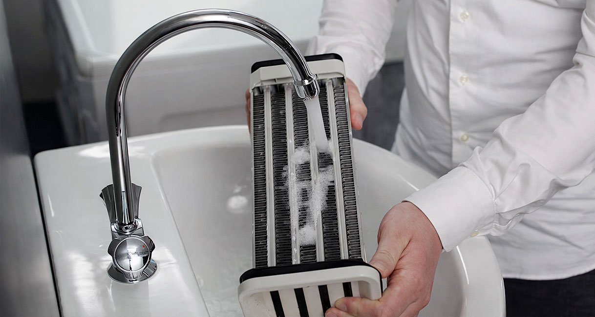 Condensor schoonmaken onder de kraan als onderdeel van onderhoud van een droger