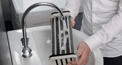 Condensor schoonmaken onder de kraan als onderdeel van onderhoud van een droger