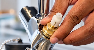 Ontkalkt binnenwerk wordt voorzichtig met de hand terug in het kraanhuis van keukenkraan geplaatst