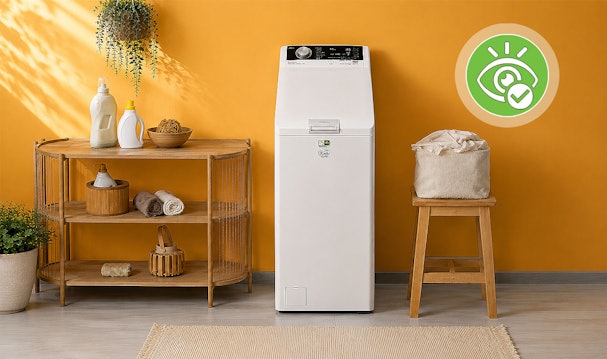 Smalle witte AEG bovenlader wasmachine naast houten kruk met wasmand in bijkeuken