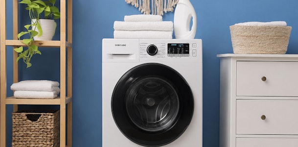 Witte Samsung wasmachine van 8 kg in een bijkeuken met wasgoed en manden