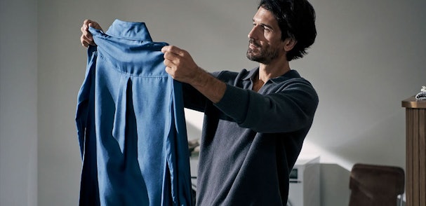 Man bekijkt tevreden een schoon blauw overhemd na het wassen