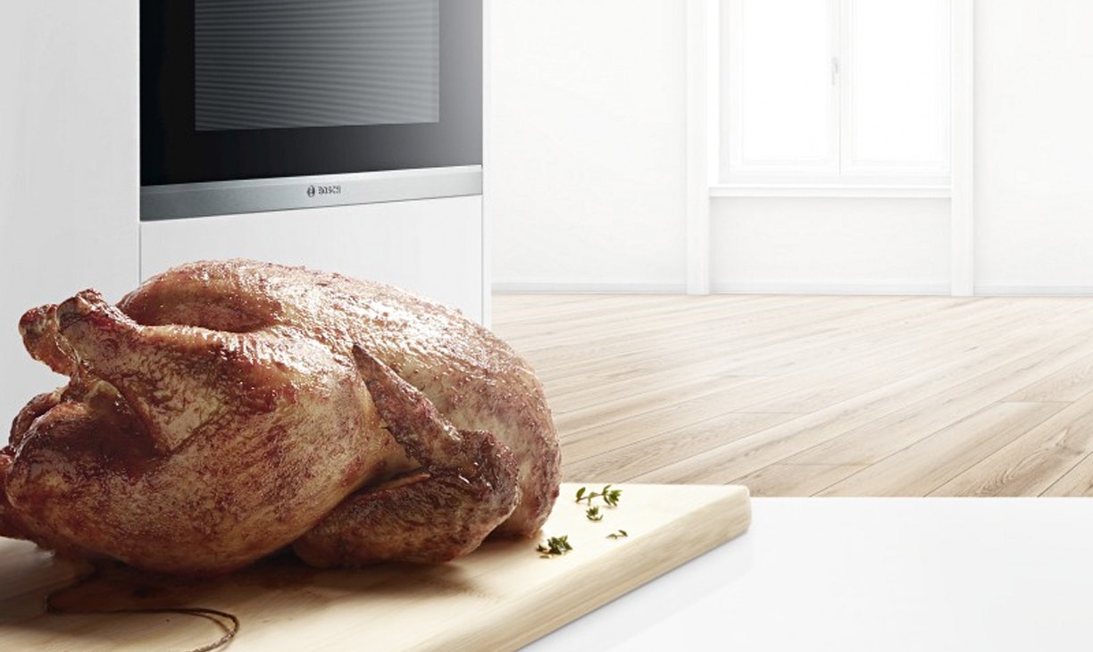 Met een kerntemperatuurmeter in de oven gebraden kip op een plank.