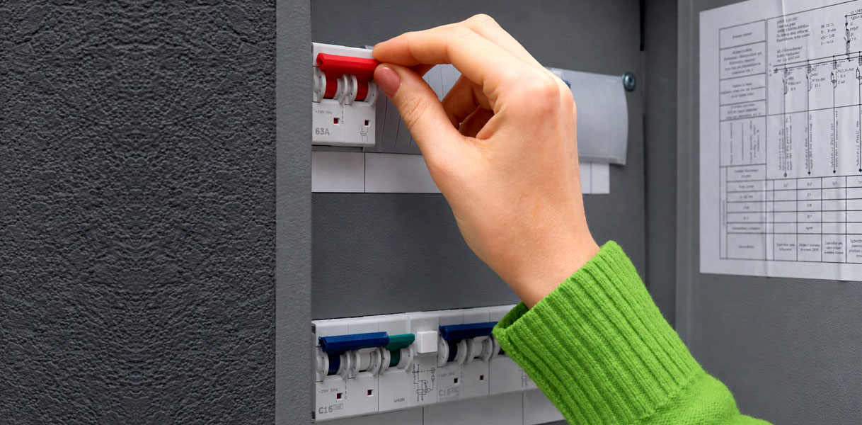 Hand schakelt een groep uit in de meterkast met het groepenoverzicht ernaast