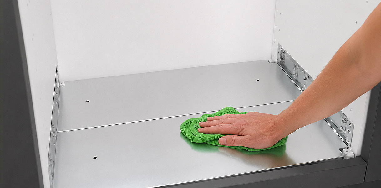 Hand veegt met een doek de bodem van de lege nis schoon voor de oven