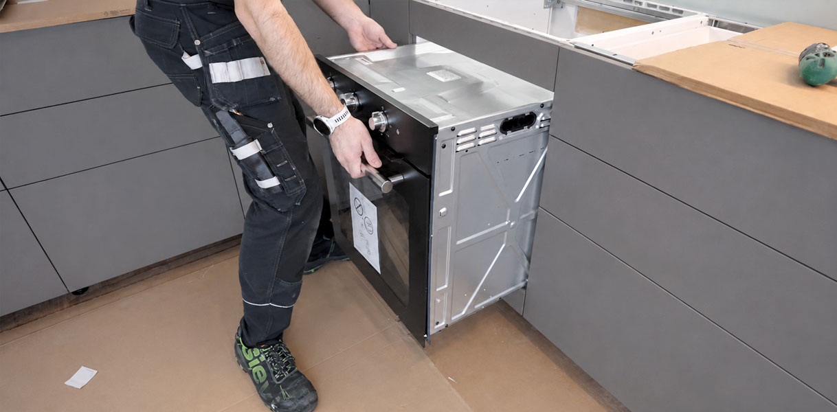 Monteur schuift de oven recht de nis in met beide handen aan het apparaat