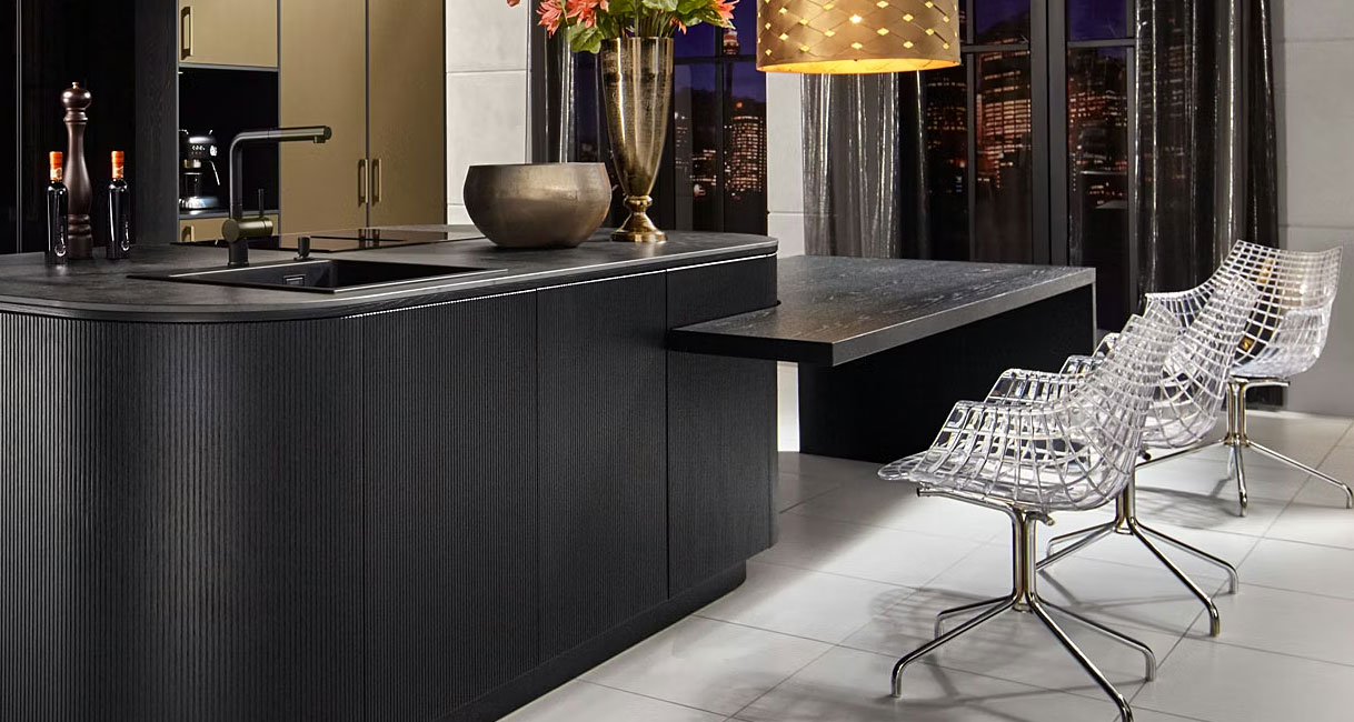 Kookeiland met subtiele overgang naar lager tafelgedeelte in donker materiaal met design stoelen