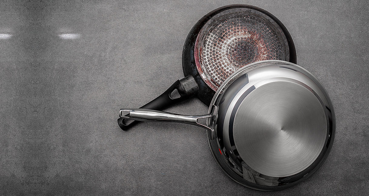 Onderkant van twee pannen waarbij een pan met magnetische bodem geschikt is voor koken op een inductiekookplaat.