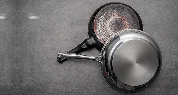 Onderkant van twee pannen waarbij een pan met magnetische bodem geschikt is voor koken op een inductiekookplaat.