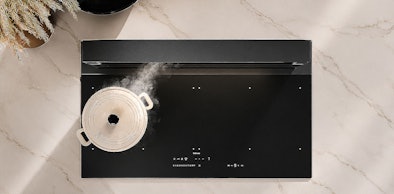 Downdraft afzuigkap naast inductie kookplaat met pan in keuken bovenaanzicht