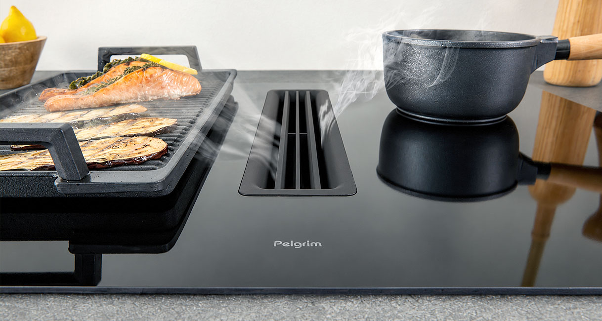 Pelgrim kookplaat met afzuiging die damp van grillplaat met zalm en dampend steelpannetje afvangt