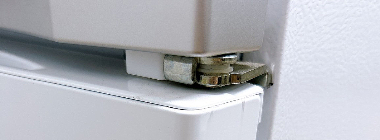 Koelkastscharnier dat piepend geluid kan veroorzaken door wrijving.