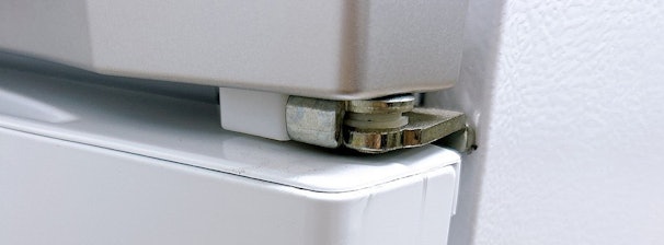 Koelkastscharnier dat piepend geluid kan veroorzaken door wrijving.