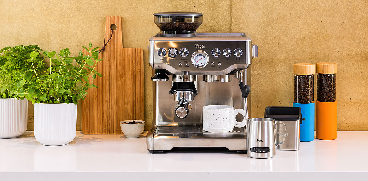 Pistonmachine met zeefdrager bonenmaler en melkkannetje op het aanrecht voor de thuisbarista