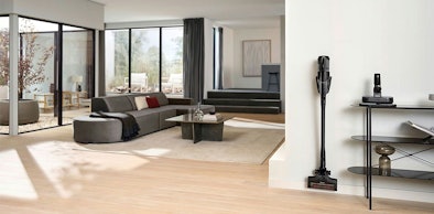 Miele Triflex HX3 Plus staat opgeladen in ruime woonkamer met accessoires op bijzettafel, geschikt voor grote huizen