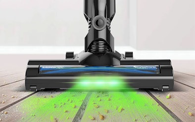 Stofzuiger mondstuk met LED-verlichting toont groene zuigkracht test met deeltjes op laminaatvloer