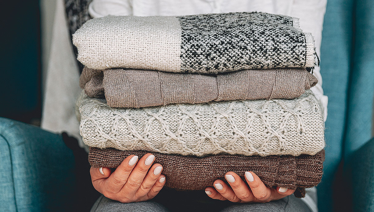 Opgevouwen truien en kleding die uit de kast komen en geschikt zijn om op te frissen in de wasdroger